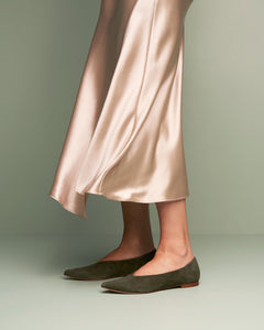 Model in satin skirt wearing Oya Ramona flat pointed toe shoe in olive green suede, low heel for extended women's sizes.